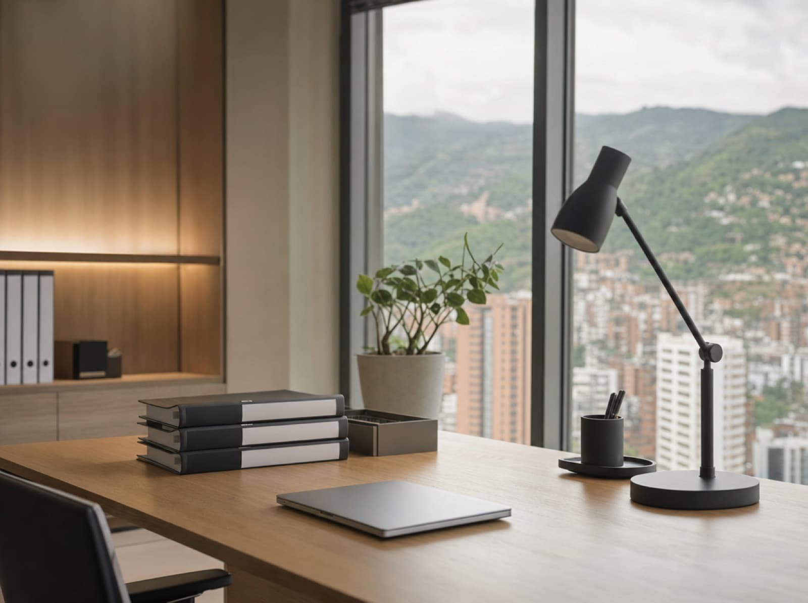 Escritorio de trabajo ordenado con archivadores, un portátil cerrado y una lámpara en una oficina de Medellín